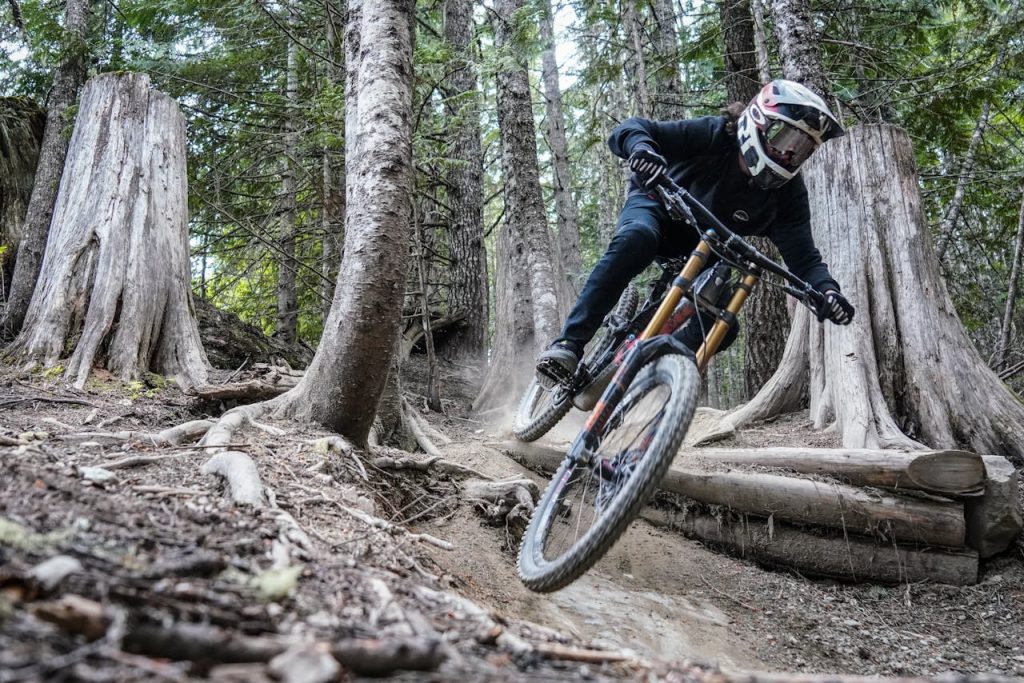 Mountain biker tackling a challenging forest trail at high speed.